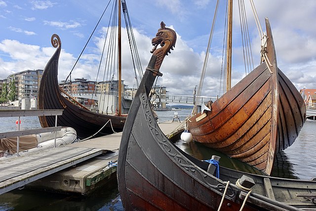 Forstavnene på vikingskip og båter fra norsk middelalder fortøyd til brygga i havna i Tønsberg i Vestfold