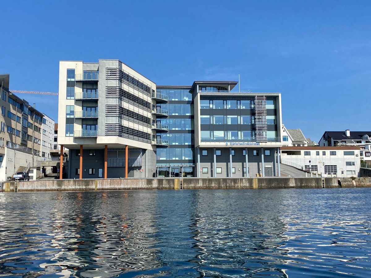 Fasaden på Sjøfartsdirektoratets hovedkontor i Haugesund i strålende sol og med blank sjø i forkant.