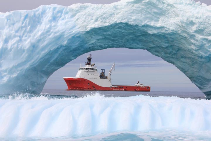 The photo displays a supply vessel seen through an arch of ice